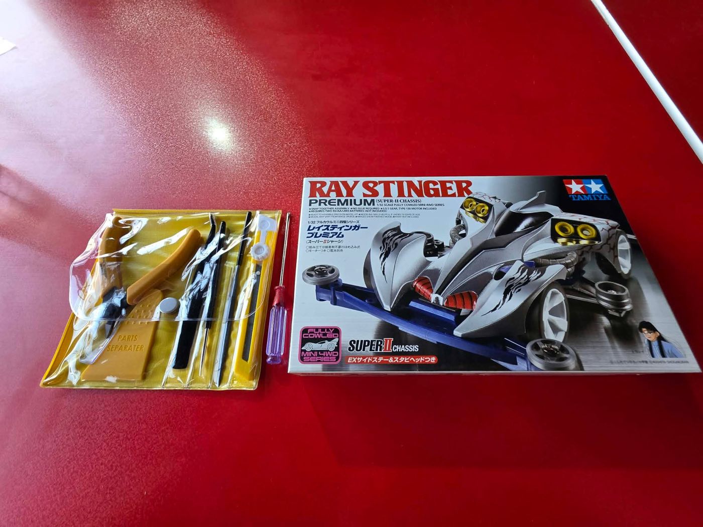 A Tamiya Ray Stinger Mini 4WD kit beside a modelling tool set